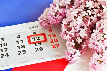 Russia Day. Holiday concept. Lilac bouquet and calendar with the date of June 12 against the background of the flag of Russia. Place for text