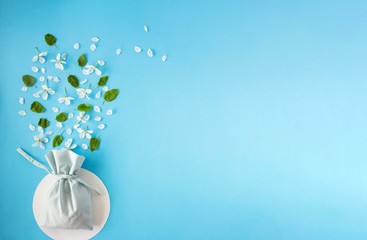 Cotton bag with white flowers and green leaves. The view from the top floral background. Flat lay