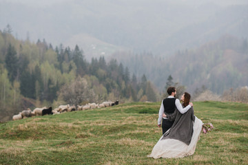 Fototapeta na wymiar Romantic, young and happy caucasian couple in wedding clothes hugging on the background of beautiful mountains. Love, relationships, romance, happiness concept. Bride and groom traveling together.