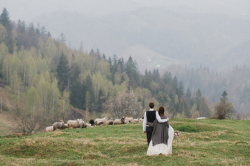 Fototapeta premium Romantic, young and happy caucasian couple in wedding clothes hugging on the background of beautiful mountains. Love, relationships, romance, happiness concept. Bride and groom traveling together.
