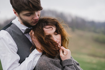 Fototapeta premium Romantic, young and happy caucasian couple in wedding clothes hugging on the background of beautiful mountains. Love, relationships, romance, happiness concept. Bride and groom traveling together.