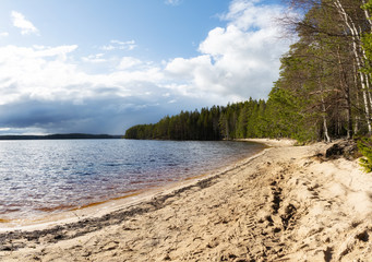 View of the Lake Haukkajarvi in Helvetinjarvi National park in Finland. Beautiful beach on the lake. Dark storm clouds on the sky. 