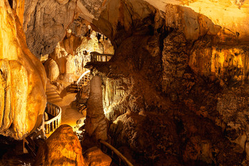 Stalactites in Limestone cave adorned with light