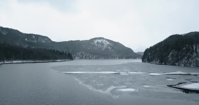 Alpsee Lake in Winter Day. Mountains and Forest. Bavarian Alps, Germany. Aerial View. Wide Shot. Drone Flies Forward, Tilt Up. 18 marth, 2019.