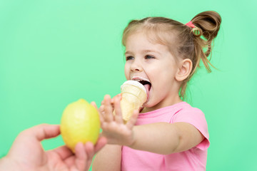 little girl 4 years old in a pink T-shirt on a green background emotionally repels the proposed lemon, chooses ice cream.