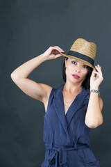 Beautiful young model in a pretty blue dress and hat on a grey background