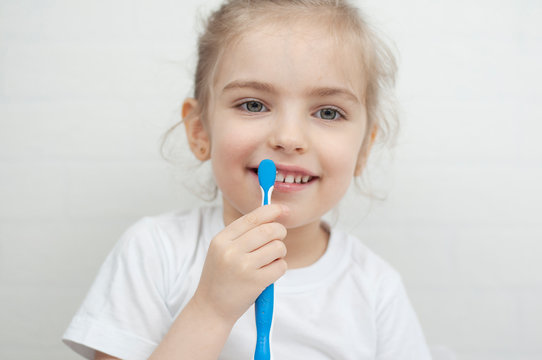 Little girl holds a toothbrush in her hands and toothpaste brushes
