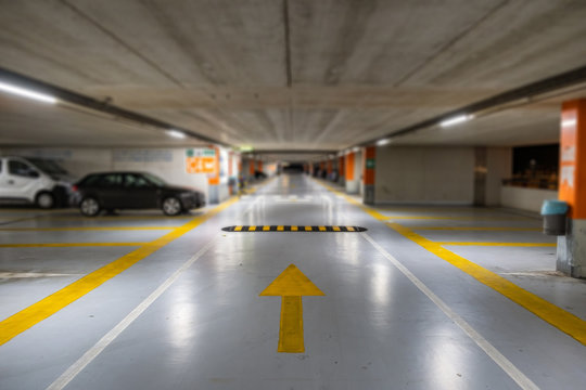 Yellow markings with blurred modern cars parked inside closed underground parking lot.