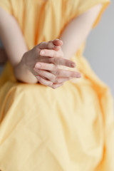 A young girl's thin hands. Girl in a yellow dress 