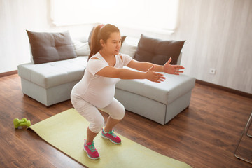 A pregnant woman works out on a yoga mat at home. Pregnancy and sports. Oga and Pilates for...