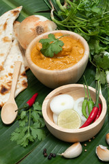 Indian food butter chicken on banana leaf background. Decorated with spice ingredient, garlic and pepper.