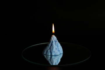 Global warming concept. Candle in the form an iceberg or glacier and mirror on black background....