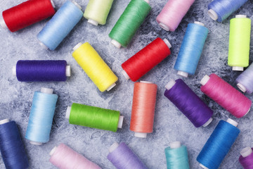 Colorful threads on bobbins, sewing set.On gray concrete background. Place for text.