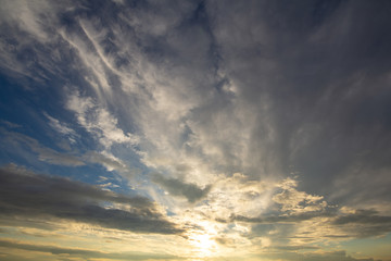 Blue sunset sky covered with white puffy clouds.