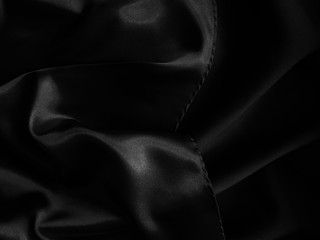 Black glossy crumpled fabric. Wavy fluid background