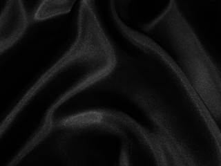Black glossy crumpled fabric. Wavy fluid background