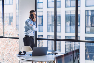 Focused businessman talking on smartphone looking through office window