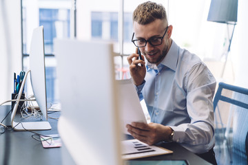 Manager checking document and talking on smartphone