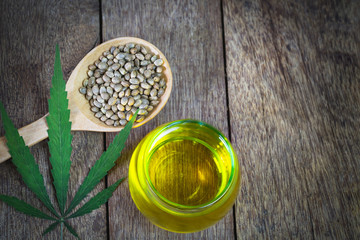 Hemp seeds and cbd hemp oil. Hemp seeds in wooden spoon and hemp essential oil in small glass bottle, medical marijuana concept.
