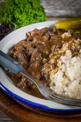 Beef stew served with barley and pickled cucumber.