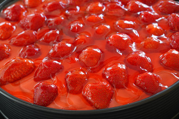 Strawberry cake in a black spring form pan - close up of jelly fruit topping,