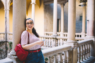 Happy adult woman using smartphone on balcony of ancient building