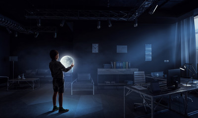 Fototapeta na wymiar Boy holding moon at night in the office