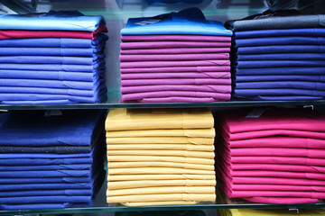Bright summer collection of clothes on the shelves. Summer clothes of different colors for sale in a supermarket.