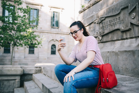 Tranquil woman taking photos during vacation in city