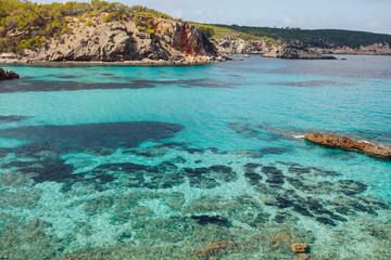 Beautiful view of Cala Portinax, Ibiza. Amazing sea view in sunny summer day from rocky coast.