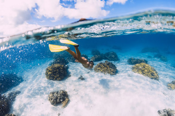Woman swimming underwater with yellow fins in ocean. Freediving or snorkeling in Mauritius