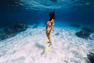 Woman swimming underwater with yellow fins in ocean. Freediving or snorkeling in Mauritius