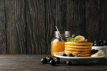 Composition with pancakes, banana, blueberry and jam on wooden background