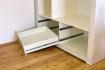 Close up of installation of wooden drawer in contemporary cupboard cabinet.