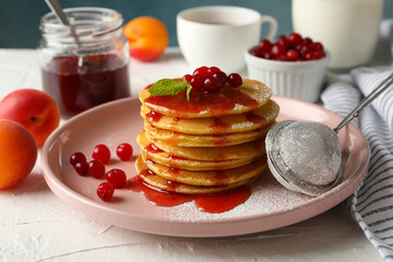 Composition with pancakes with jam and cranberry on white table