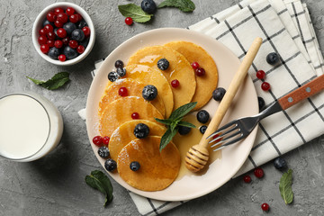 Plate of tasty pancakes with berry on gray table. Composition of sweet breakfast