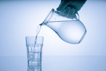 Pitcher with drinking water and a glass with a drink, blue tone