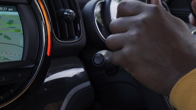 A close up shot of a black man using his indicator signal , light in his car