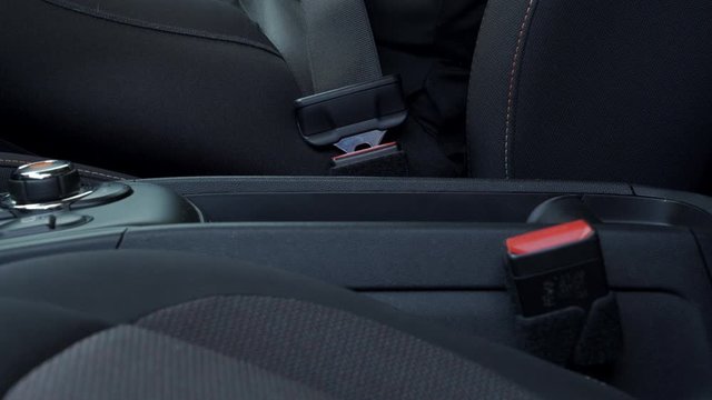 A close up shot of a caucasian woman fastening her seat belt in her car.