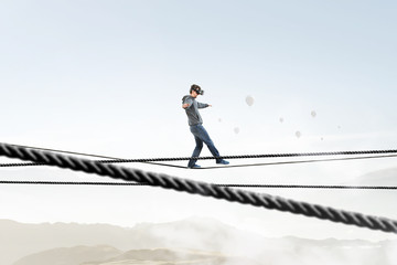 Man wearing virtual reality goggles and balancing on rope