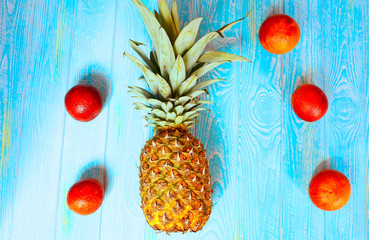 Pineapple and five red oranges on a blue wooden background. Summer concept. Fruits and vitamins....