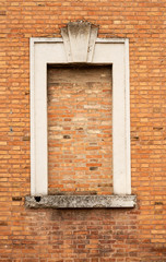 Old wall with a window closed with bricks, Ferrara Italy