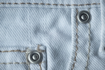 Macro texture with white and blue denim with rivets and a seam. Textile, fabric