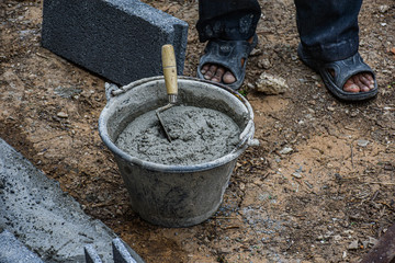 Wet cement mixing with trowel in the bucket waiting for the worker to continue foundation base concrete work for house maintenance