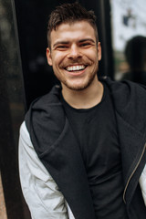 Fototapeta premium Portrait of a young man walking around the city. Brunette, beard. Cheerful, beautiful smile.