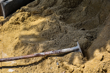 A heavy duty hoe construction equipment left on sand pile in the shade at site ground after working hard for house maintenance