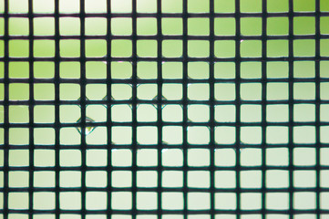Metal mesh with water drops on a colorful background