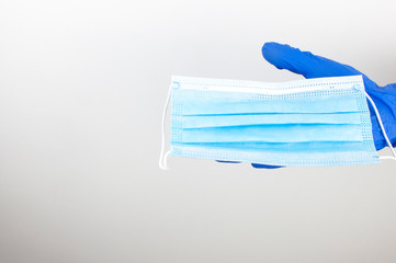 Woman hands holding facial medical mask, white  background, close up, copy space. Flu epidemic, allergy season. The most sought after coronavirus/covid-19 protection item in worldwide.