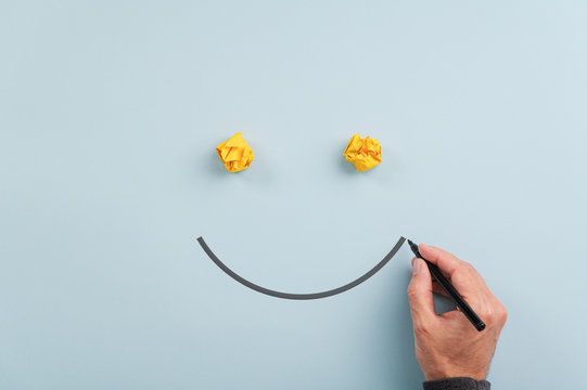 Male hand drawing a smiling face with black marker