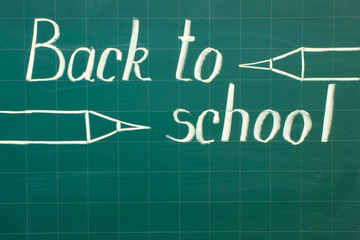 White chalk writing on a green chalkboard - back to school close-up and copy space.